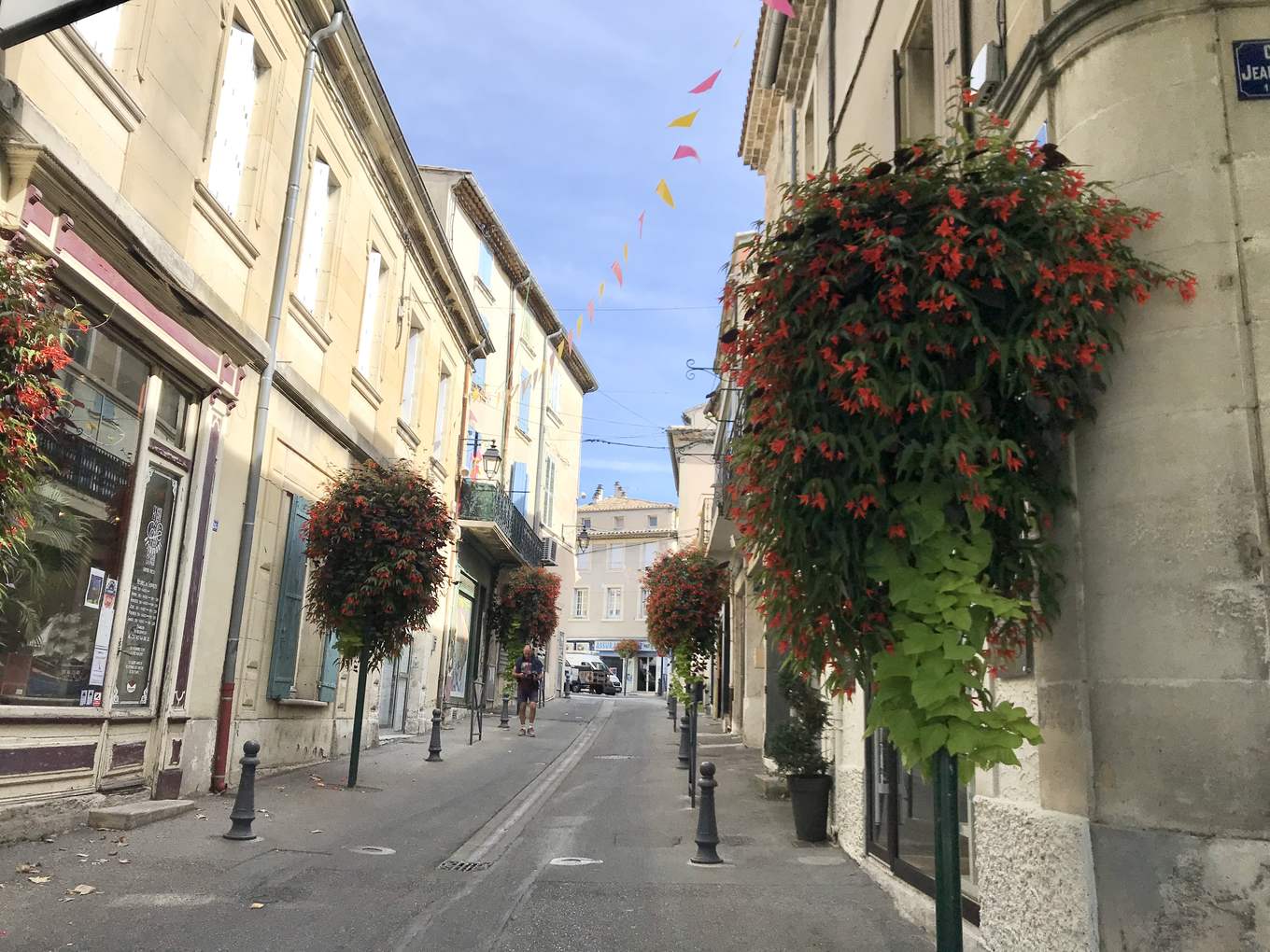 Une rue du centre ancien de Valréas, façades de pierre, suspensions fleuries et guirlandes